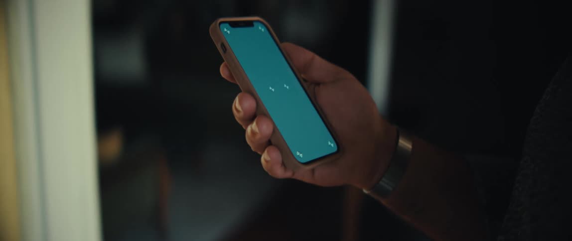 Man walks through a room looking at his phone in his hand