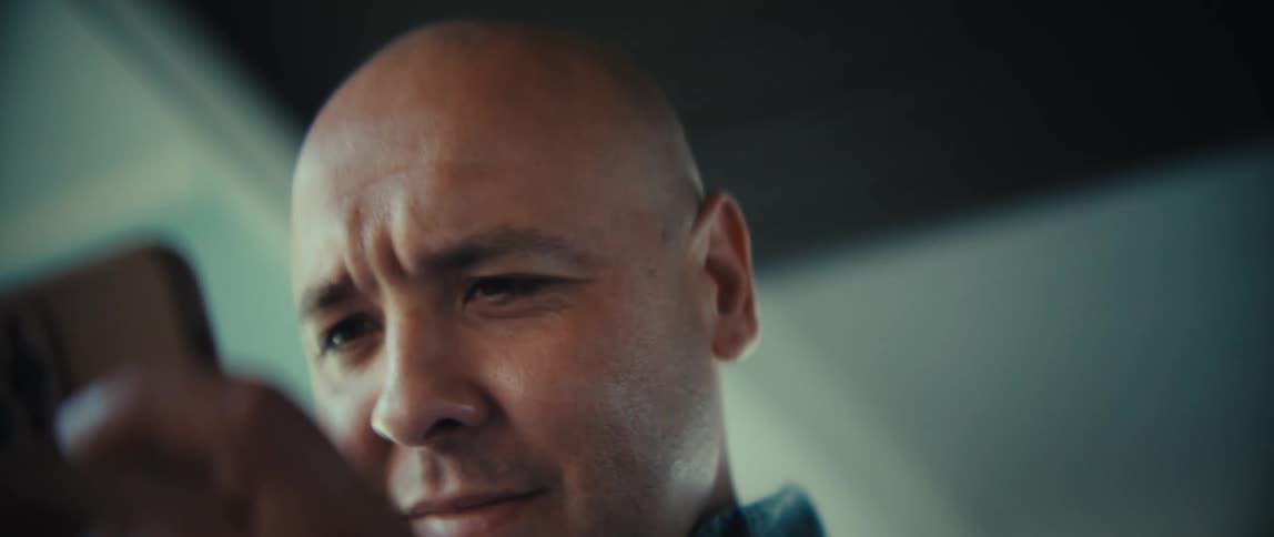 Man looking closely at smartphone with focused expression indoors