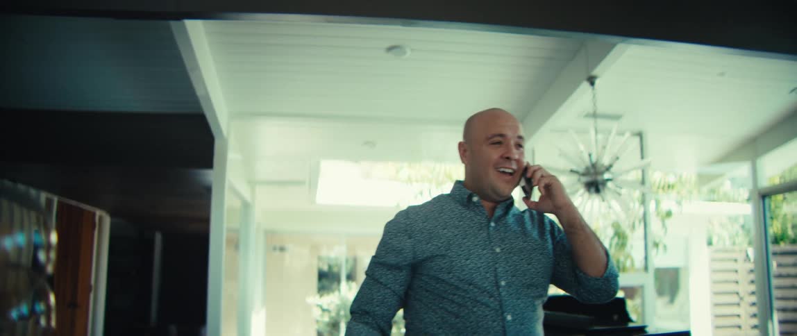A man talking on a phone while walking around in a house