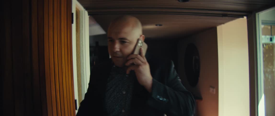 Man opens the door and walks into a house as he talks on his phone