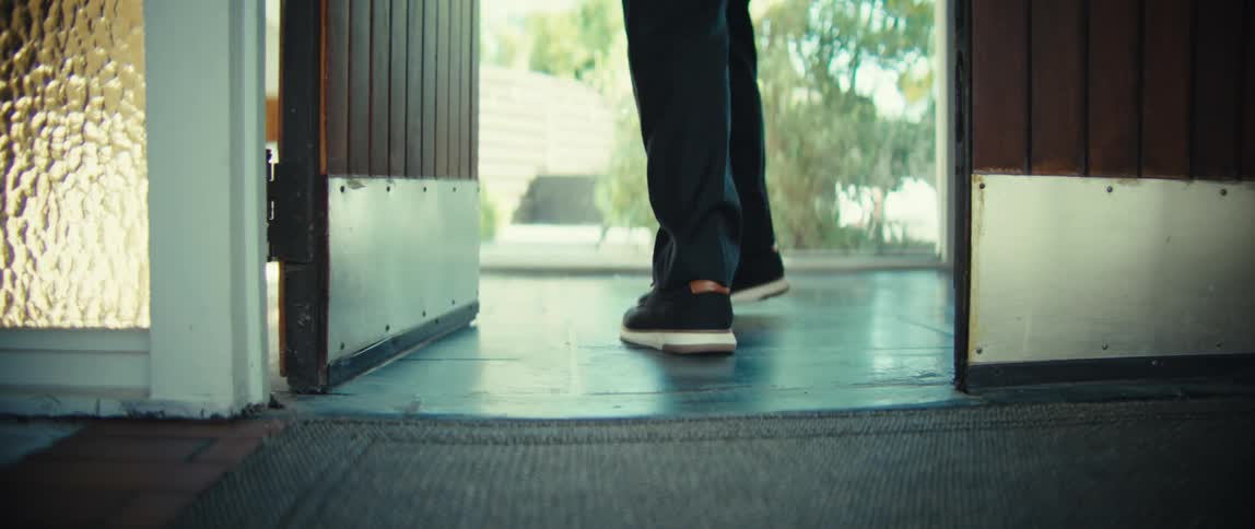 The man exits the home through the door