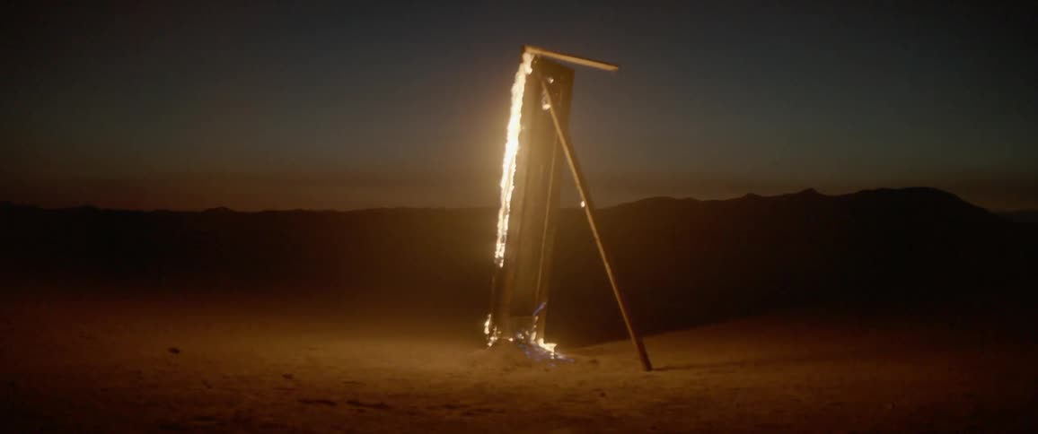 A propped up piece of wood burns at dusk