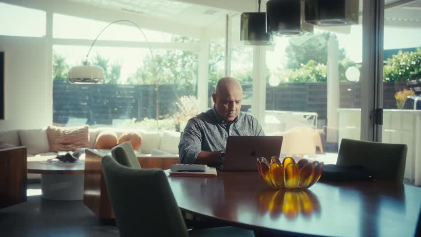 Man sitting at a table reading on a laptop computer