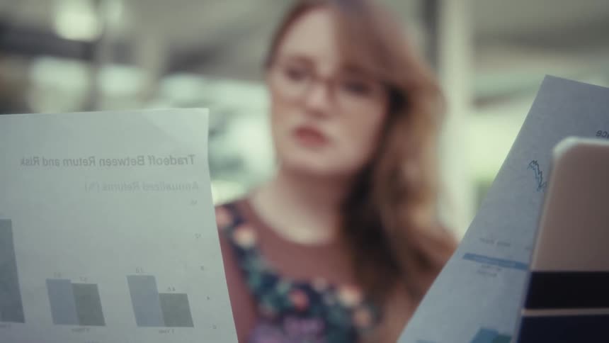 The woman is talking while looking at paperwork