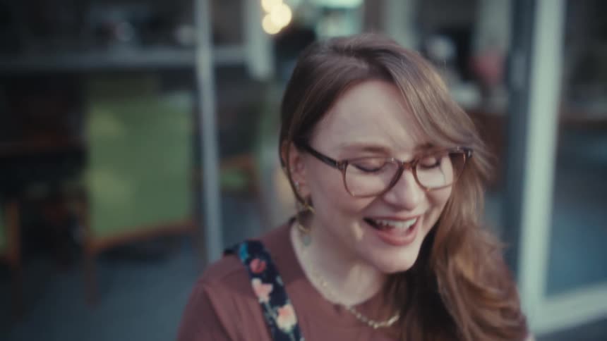 Woman wearing glasses raising her arms with expression of satisfaction outdoors
