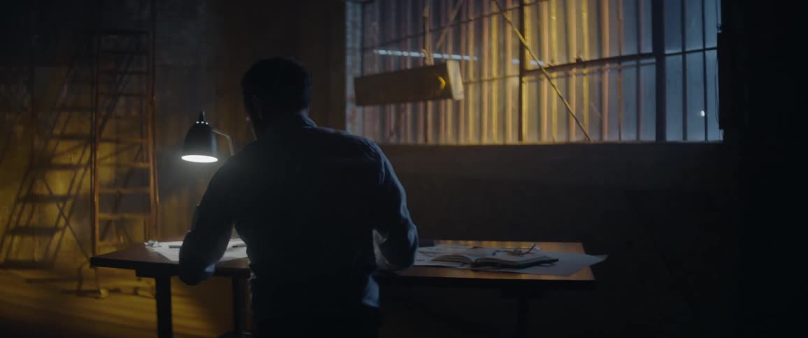 Man works in a dim workshop at a desk