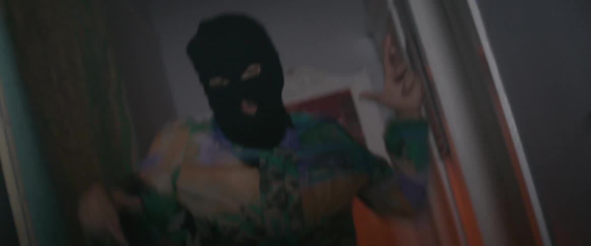 Man wearing full face mask is dancing vigorously inside house in flashing lights