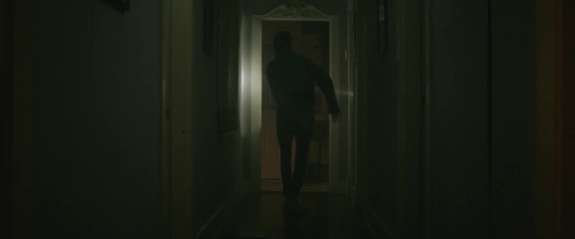 Man dancing in dark hallway while flashlights flash around him