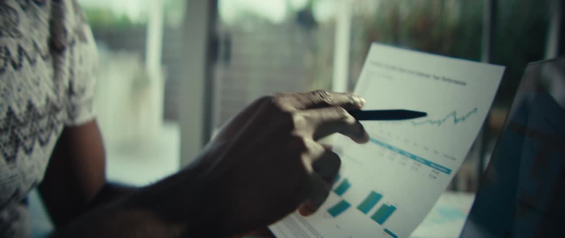 The man points to a line graph on the paper