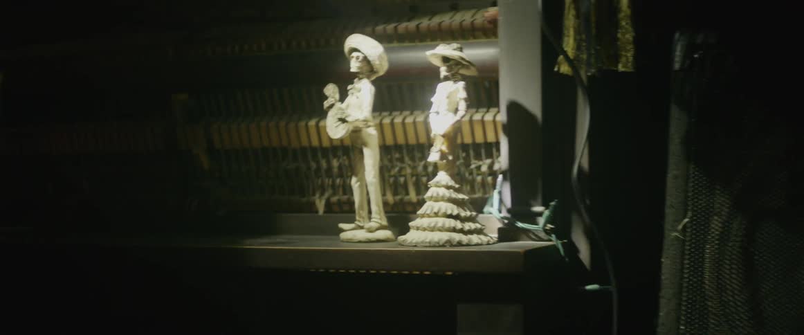 A flashlight illuminates figurines sitting on a piano