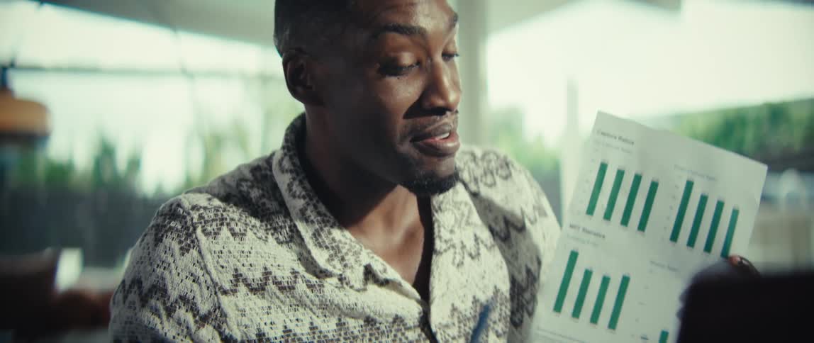 A man smiles while talking about a printout with graphs on it