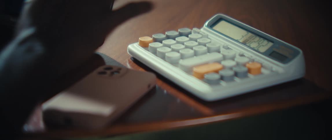 The man types on both his laptop and calculator