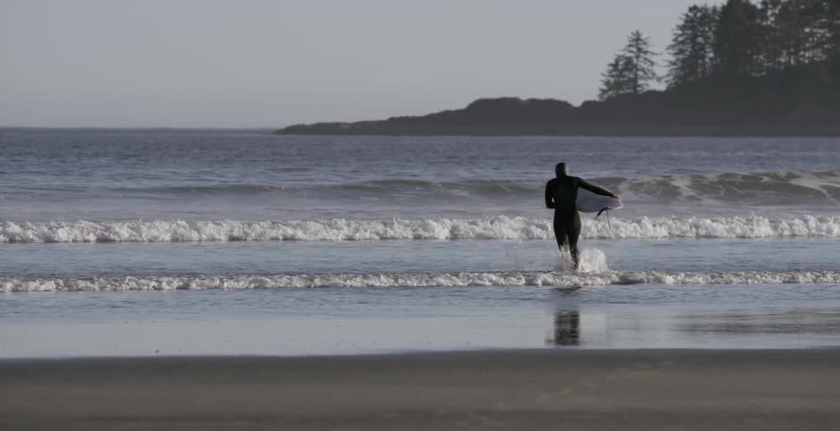 Surfer heading towards the water while carrying their board
