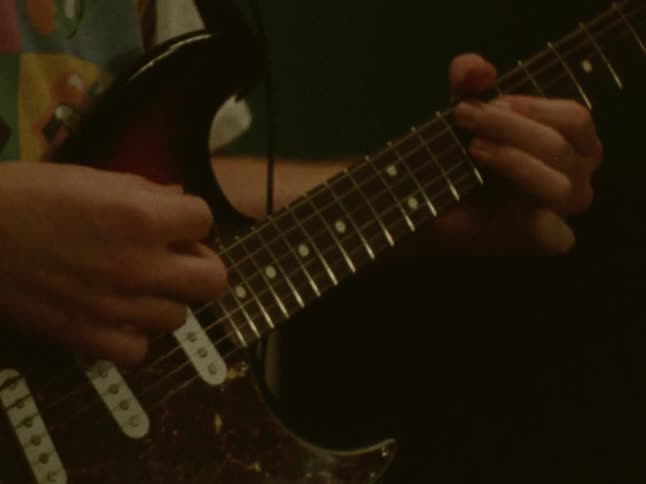 A man playing a guitar in a dark setting