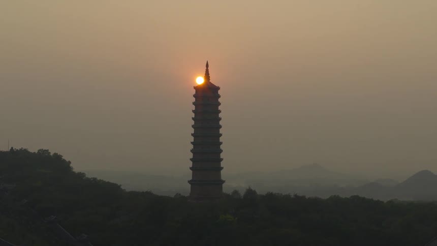The sun slowly rises above the tower