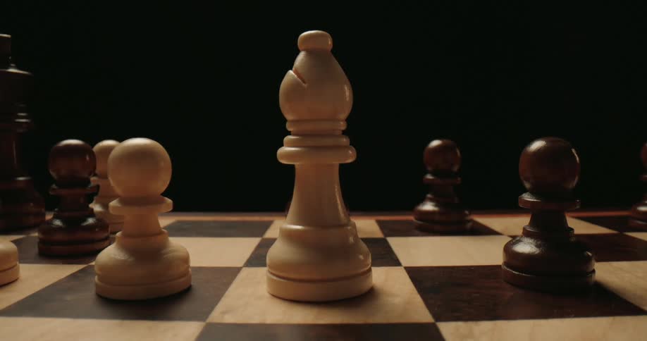 A person playing chess moving a piece with his hand in a dark room