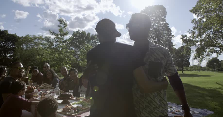 Two men greeting each other at a picnic gathering on a cloudy day