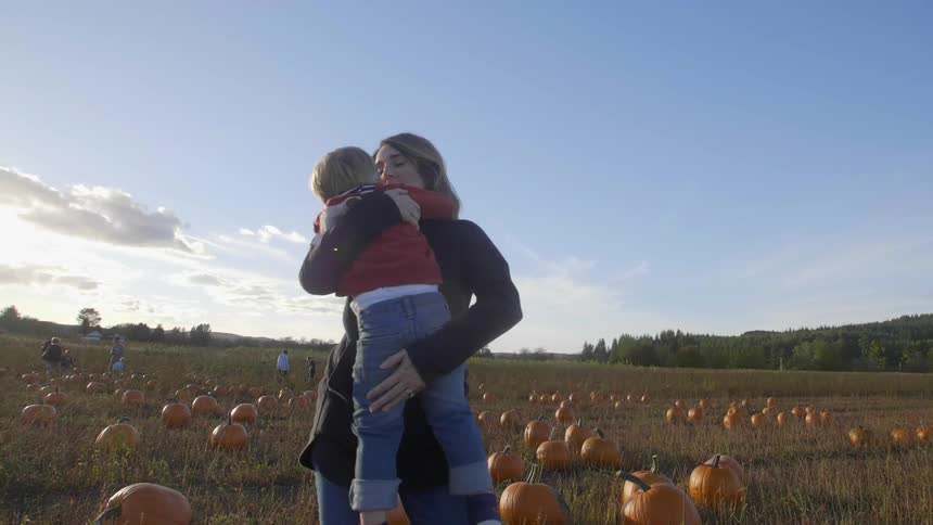 A woman carries a child through a field
