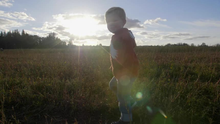 A boy walks in a field on a sunny day