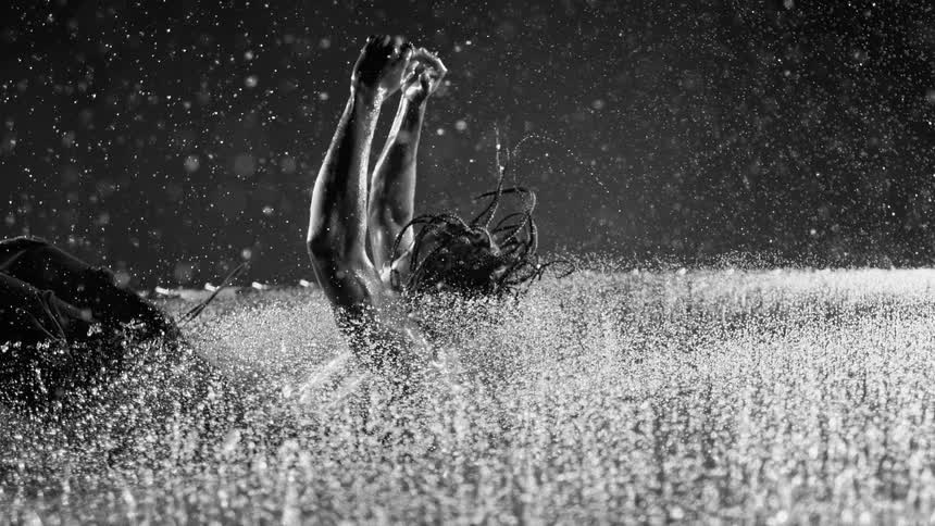 Man falls backward into the water as raindrops fall