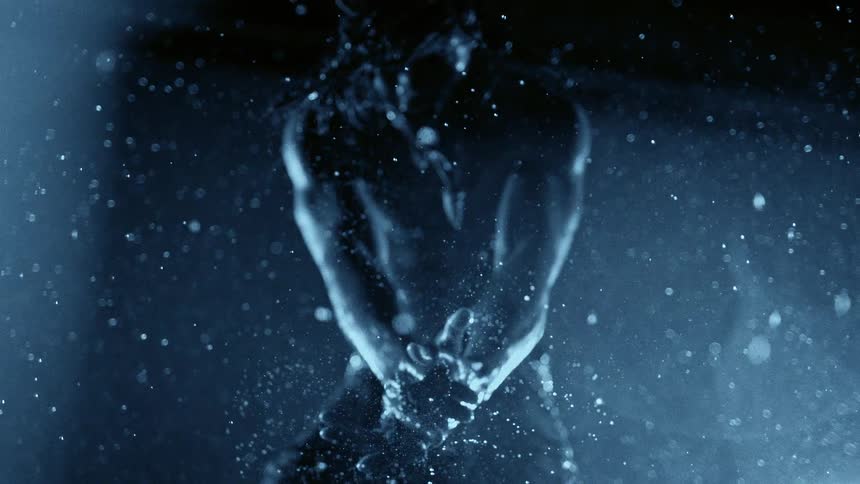 The man claps his hands together in the water