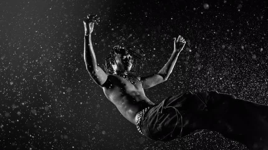 Bare chested man wearing stylish pants with metal accessories falls backward at night while it rains