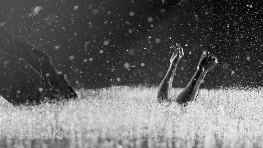 Person falling to the wet ground with arms raised in heavy rain