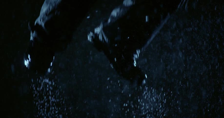 Feet in motion with water splashes in dark scene