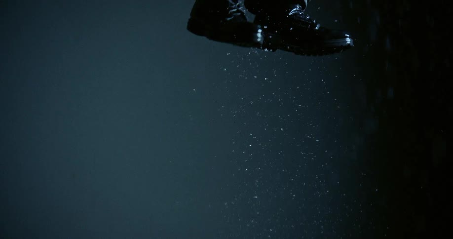 Legs jump over a wet surface with water particles scattered in the air