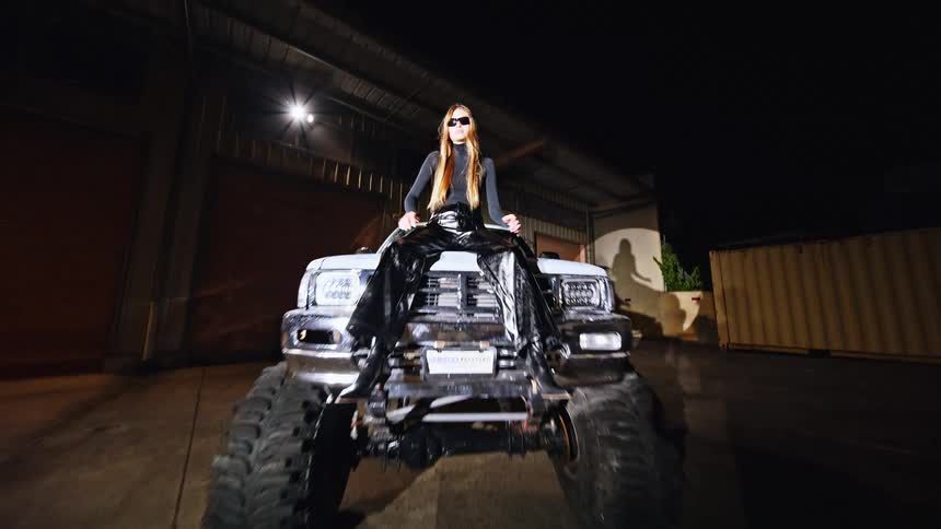 A woman is sitting on the hood of a truck