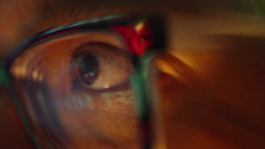 Closeup of eye behind colorful eyeglasses with reflection on the lens