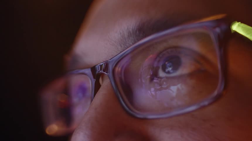 Persons eyes wearing glasses reflecting screen light