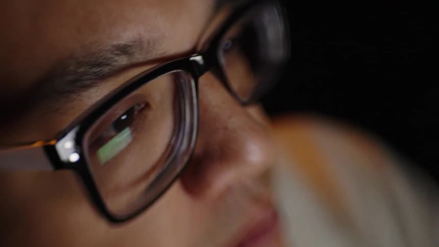 A man with glasses looking at a screen
