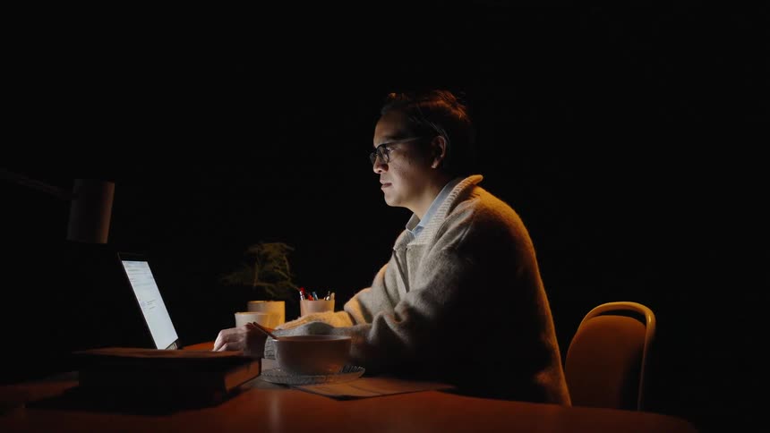 Man sitting at a desk typing on the keyboard of a laptop computer