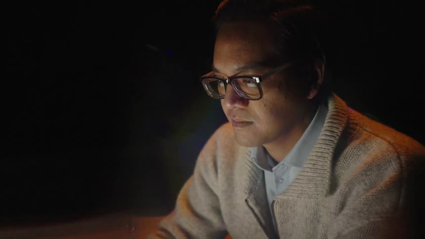 A man sitting in a room looking at a screen