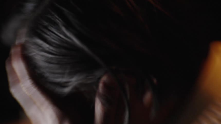 An exhausted person takes off their glasses and rubs their face and eyes in a dimly lit room the closeup shots emphasize their physical fatigue and the stress of working late into the night