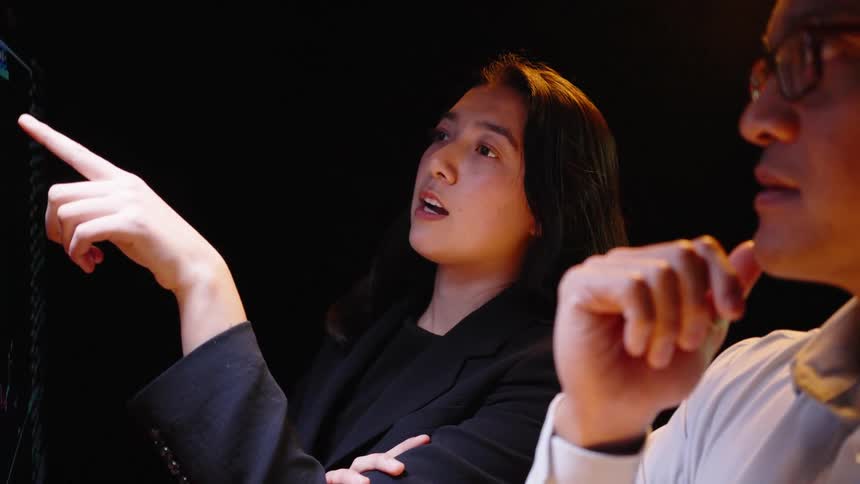 Two analysts review financial data on the digital screen