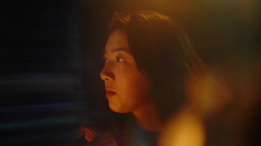 Woman observes financial charts projected on a screen with colorful lights