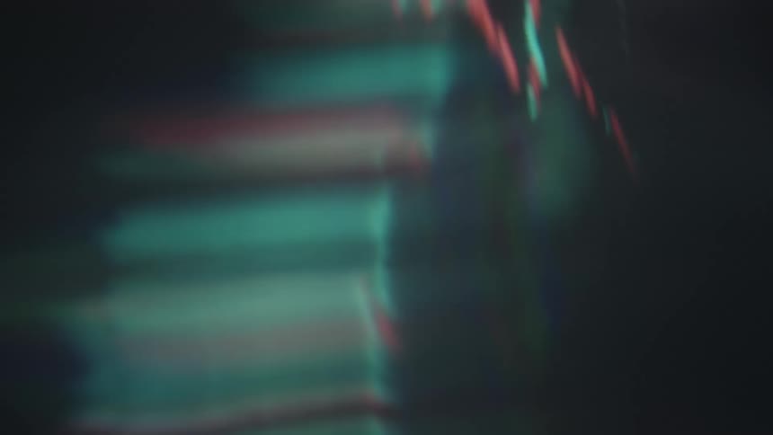 Blurry red and green bars move across a dark screen creating a distorted and colorful light effect in a dim setting