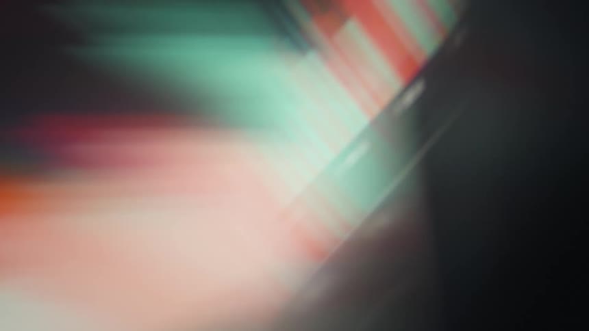 Blurry red and green bars move across a dark screen creating a distorted and colorful light effect in a dim setting