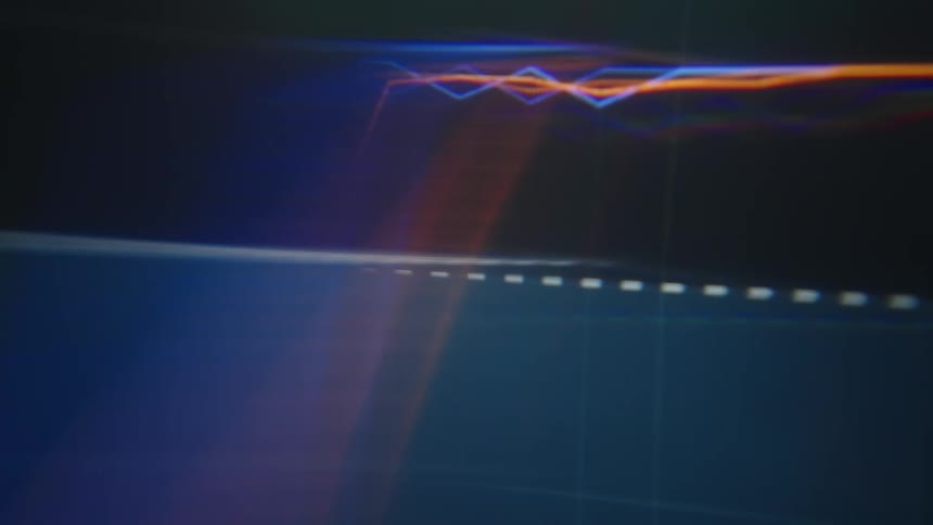 Vibrant blue and orange neon lines move across a dark digital screen with a grid pattern and soft light leaks creating a modern and tech focused background