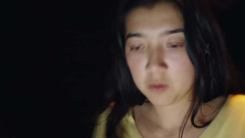 Woman illuminated by screen light in a dark environment