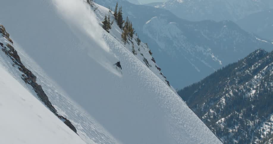 Snowboarder slides down a steep mountain slope