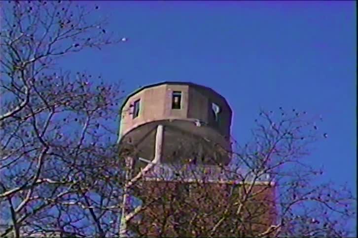 Cylindrical water tower elevated above brick building