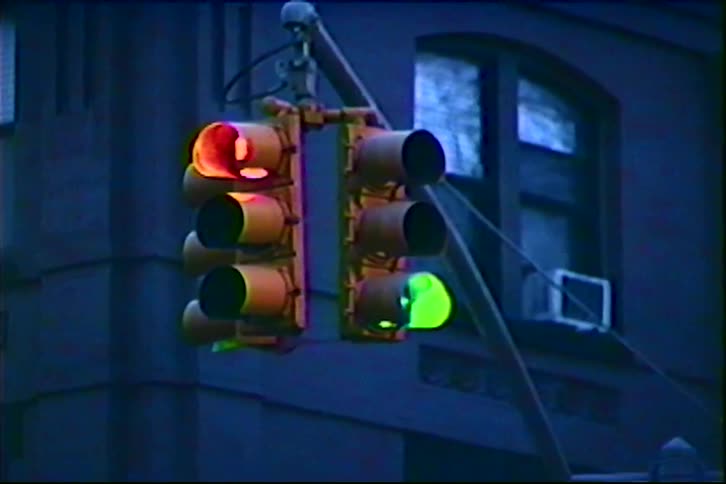 Suspended traffic lights showing red and green simultaneously in front of building with arched windows