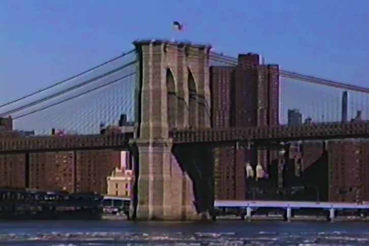 Suspension bridge over a river with buildings in the background