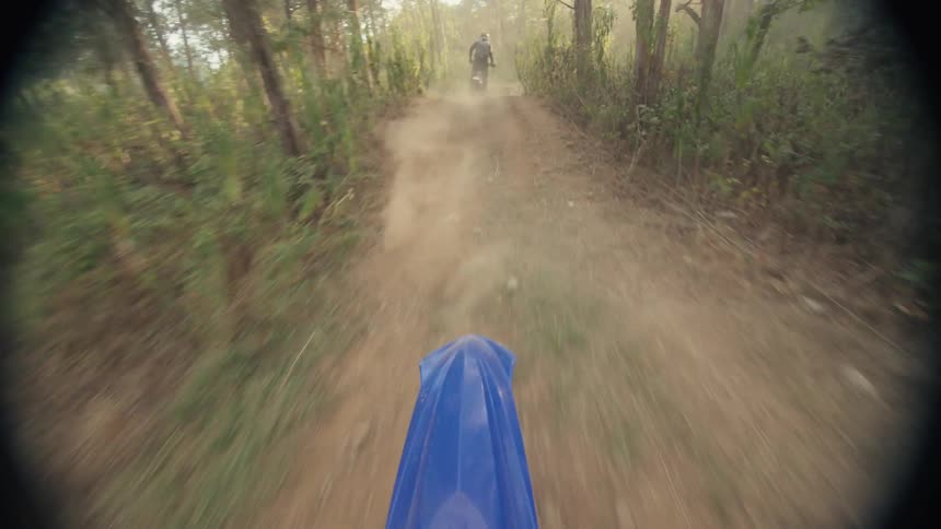 Point of view of a rider on a dirt bike following another at a high speed