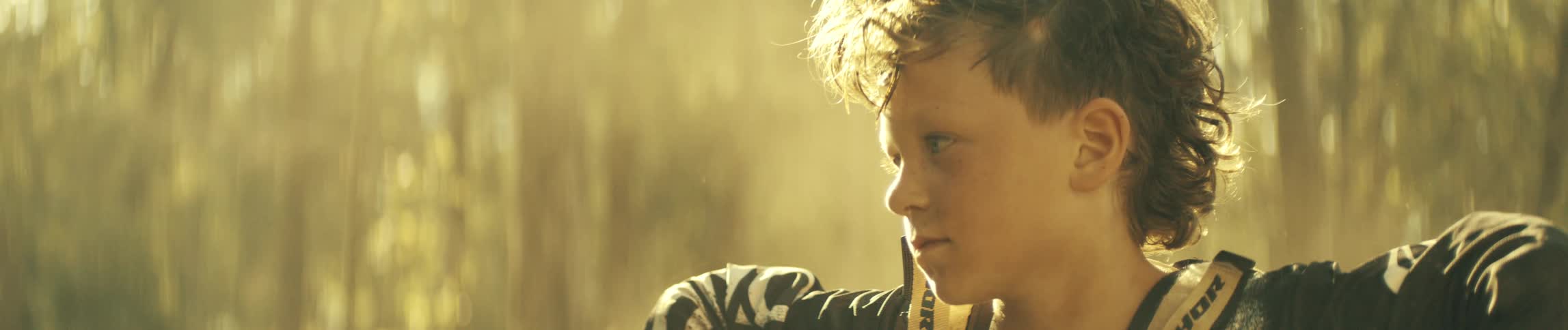 Youth stares while in the sunny woods