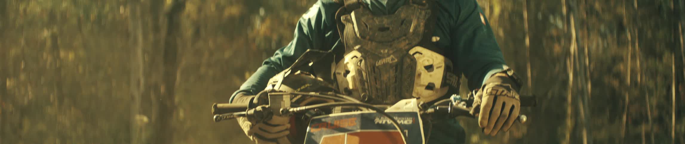 The man sits on his dirt bike on the forest trail