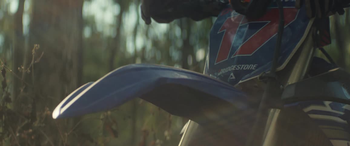 The dirt bike is parked in the forest